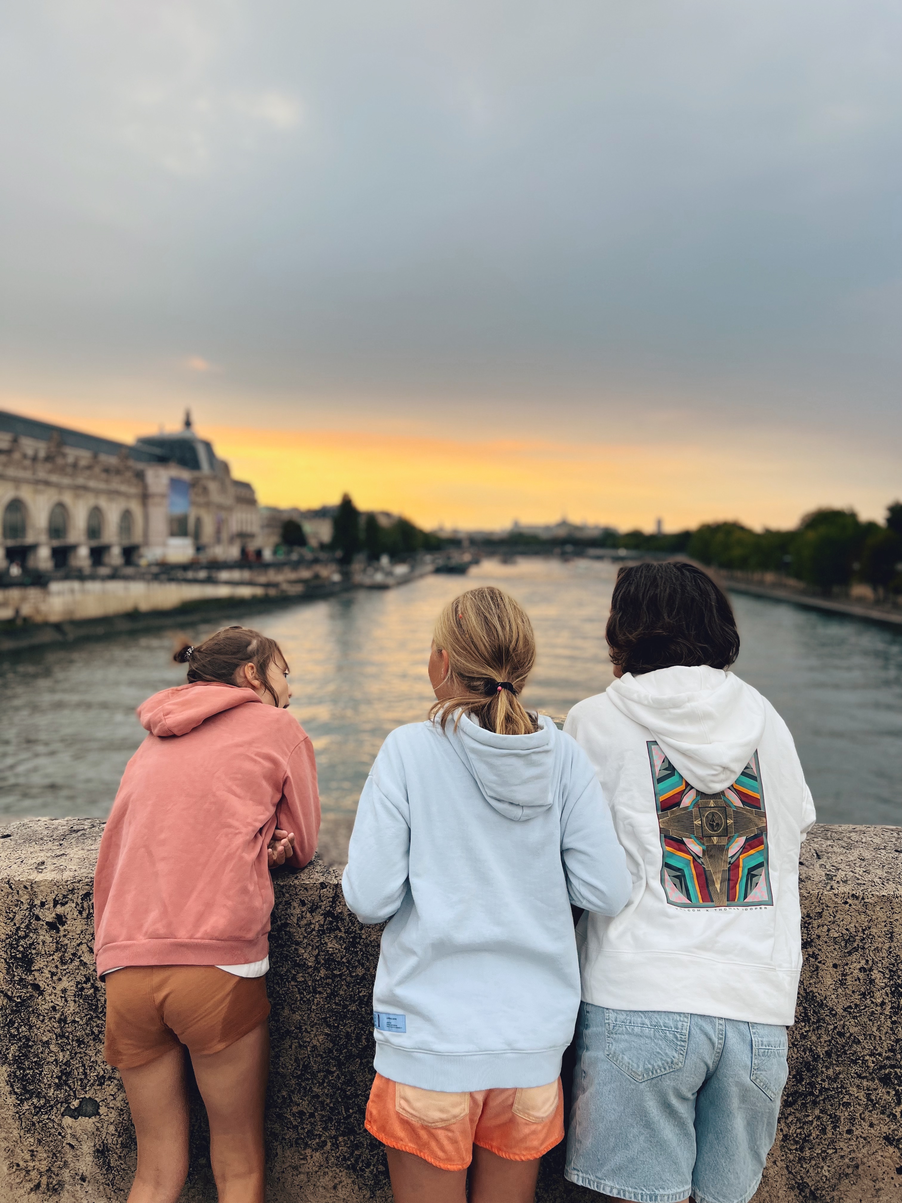 De meisjes kijken uit over de Seine met zonsondergang