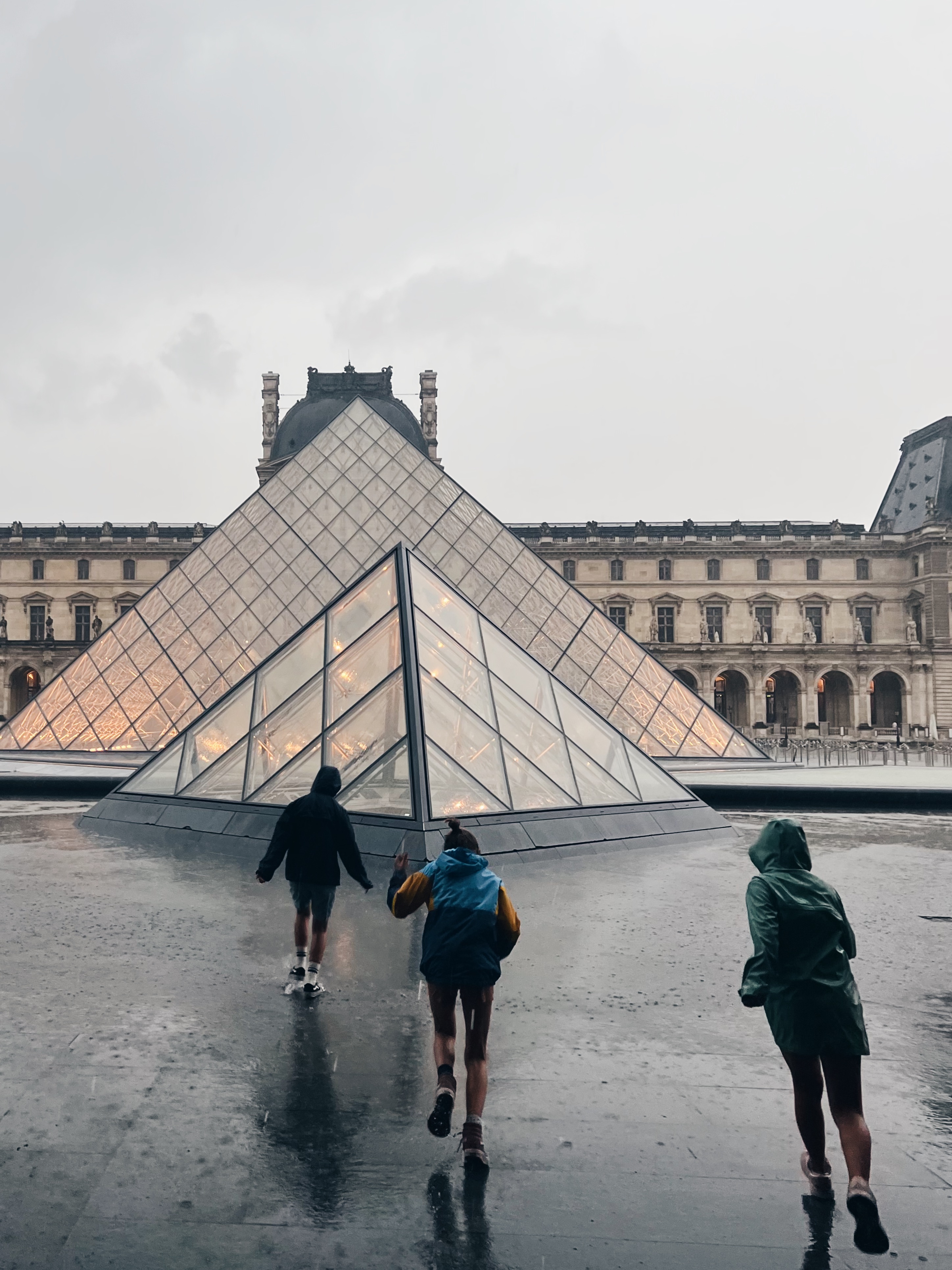 De meisje door de regen op het plein van het Louvre